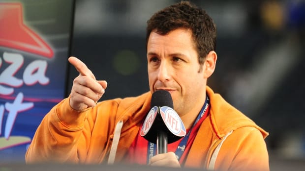 Movie actor Adam Sandler points holding a mic as he talks before Super Bowl XLV